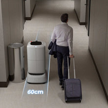 Load image into Gallery viewer, FlashBot Max passing a traveler with rolling luggage in a narrow corridor
