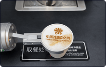 Load image into Gallery viewer, A Useabot Single-Arm Robotic Coffee Station by Elite Robots displays a latte with “CHINESE OPERA CULTURE WEEK” in English and Chinese beside a decorative logo, set on a black surface with white text. Available in enclosed or open-style workbench models.
